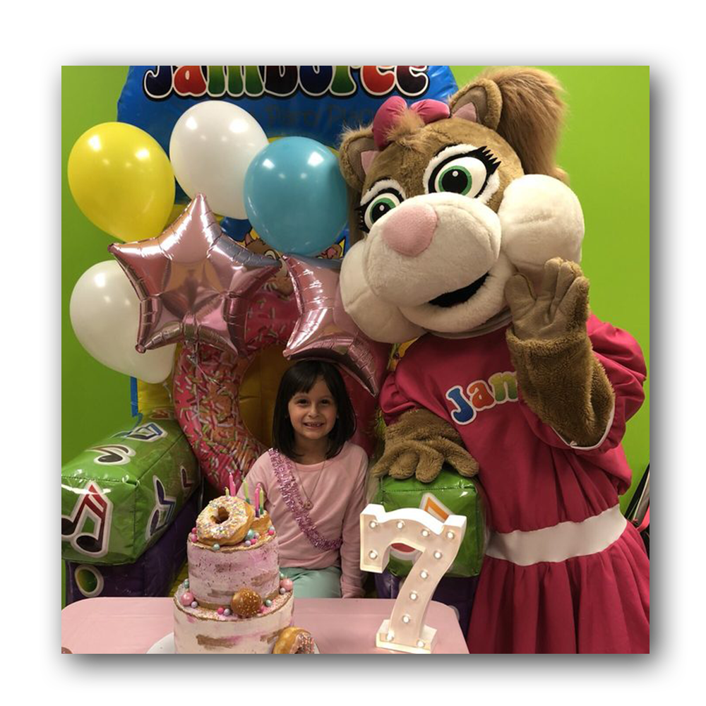 young girl posing next to character and balloons