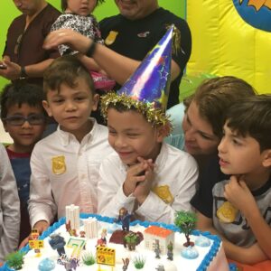 a birthday kid surrounded by friends in front of their cake