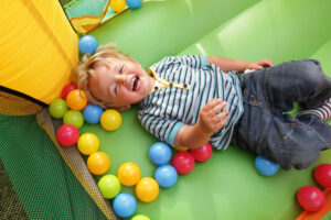 A toddler plays in a ball pit in a bounce house