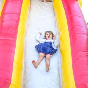 A toddler sliding down a bouncy castle slide