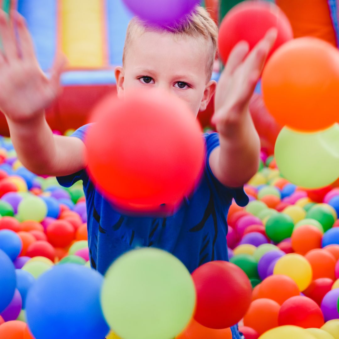 child throwing balls in ball pit