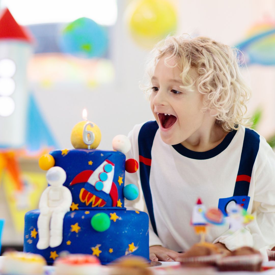 A child with a space themed birthday cake