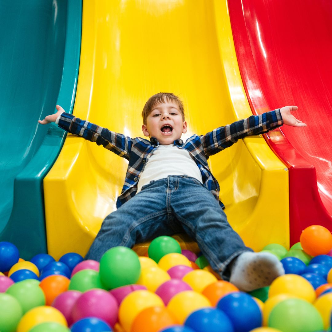 A child going down a slide into a ball pit